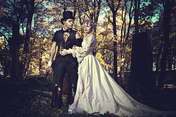 Dressed in wedding clothes romantic zombie couple walking on the abandoned cemetery.